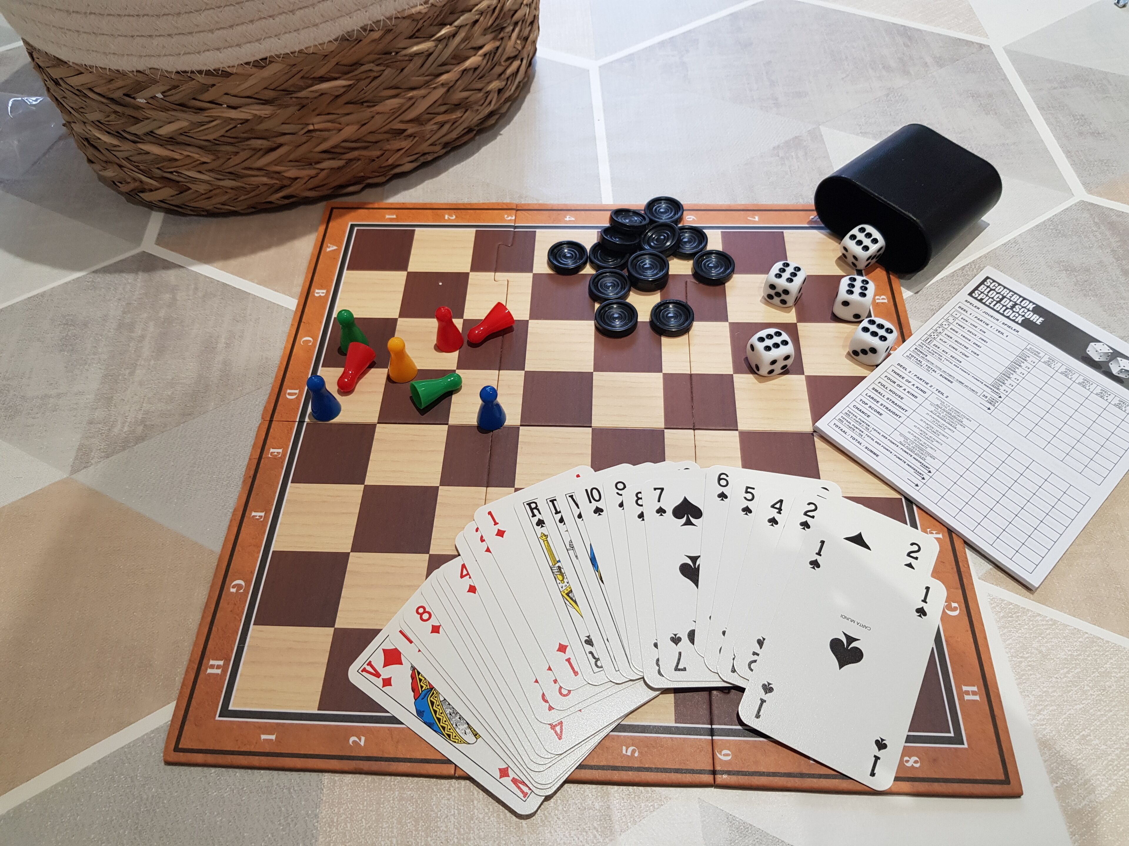 A checkered game board with dice, playing cards, and a rulebook.