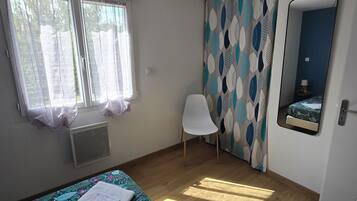 Une chambre à coucher avec un lit, une chaise, une fenêtre et un miroir.