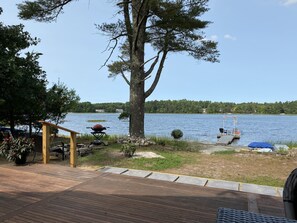 A lakeside deck with a grill, outdoor seating, and a dock extending into the water. - Onset beach, Cape code , Blackmore pond, private waterfront cottage (West Wareham)