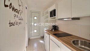 Una cocina moderna con armarios blancos, encimera de madera, pileta de acero inoxidable y un microondas.