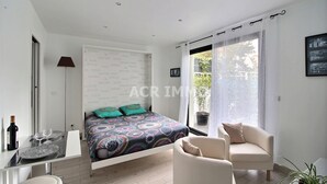 Un dormitorio moderno con una cama, un sofá, una mesa de comedor y un ventanal grande.