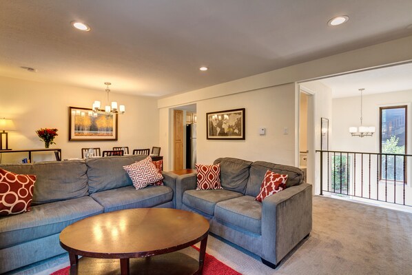 A living room with two grey sofas, a wooden coffee table, and a red rug. There are two chandeliers and framed pictures on the walls. - Hike, bike or explore Breckenridge just minutes from your doorstep (Breckenridge)