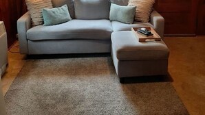 En stue med en grå sofa, en skammel og en lampe.