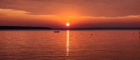 A sunset over a calm body of water with a boat in the foreground.