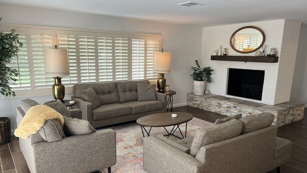 A living room with a grey sofa set, a coffee table, a fireplace, and a large window with blinds. - Casa de La Cruz - 3BR 3BA -w/ Plasma Air Technology 2,200sf Sleeps 10  (El Paso)