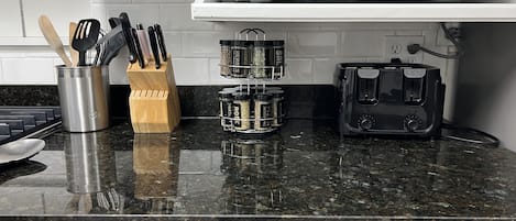 A kitchen counter with a microwave, spice rack, knife block, and toaster.