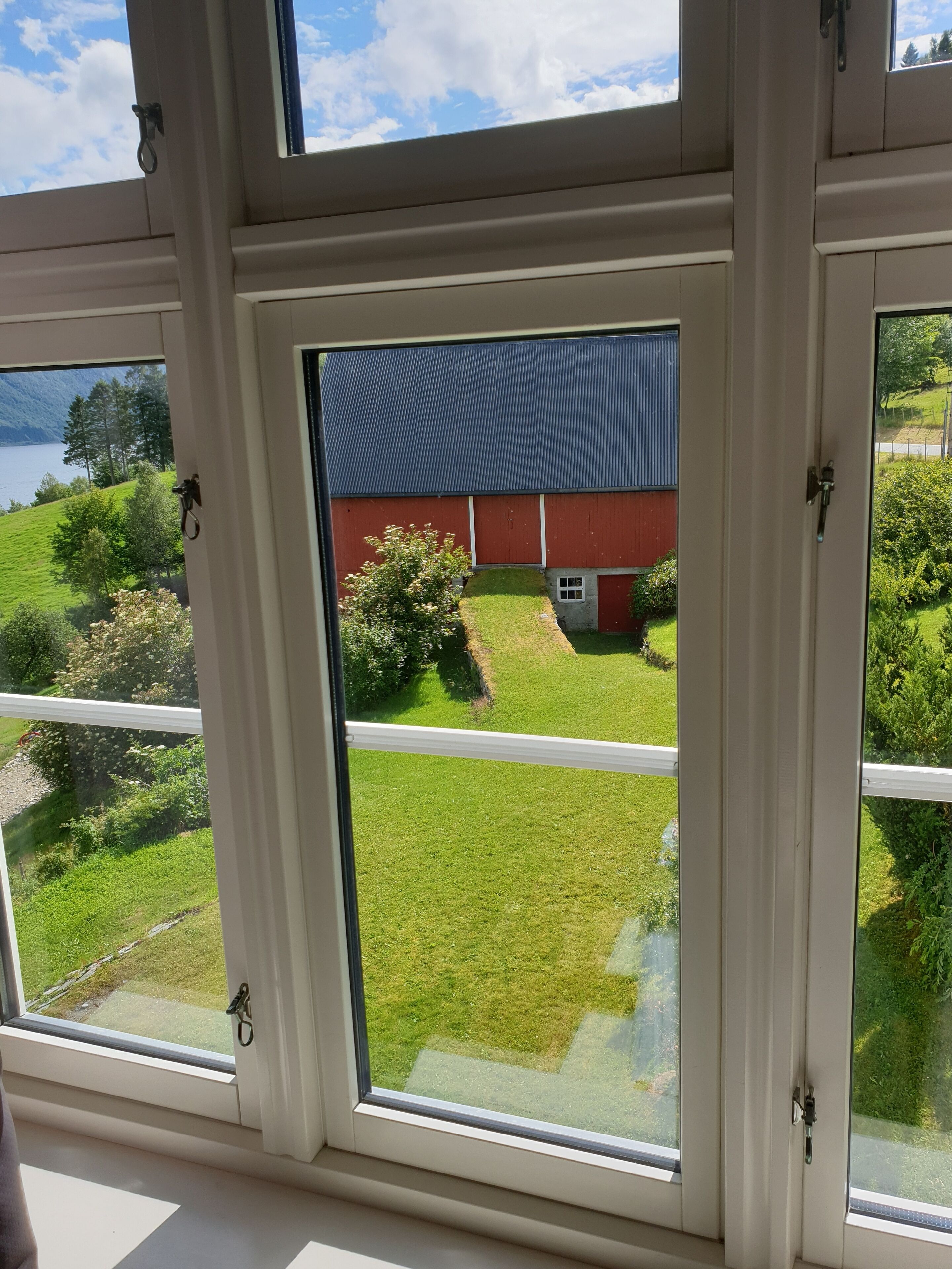 A room with a large window offering a view of a red barn and green landscape.