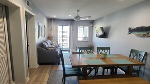 A dining area with a wooden table and benches, a gray sofa, and a ceiling fan.