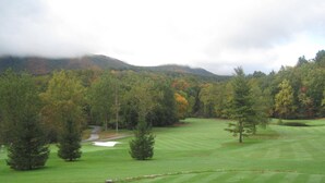 A golf course with a well-maintained green, sand bunkers, and a variety of trees in the background. - Beautiful Mount Mitchell Home - Stunning views, decks & hot tub & endless hikes (Burnsville)