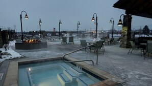 A heated outdoor pool area with lounge chairs and a fire feature.
