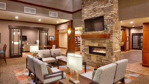 A lobby with a stone fireplace, comfortable seating, a flat-screen TV, and a well-lit interior.