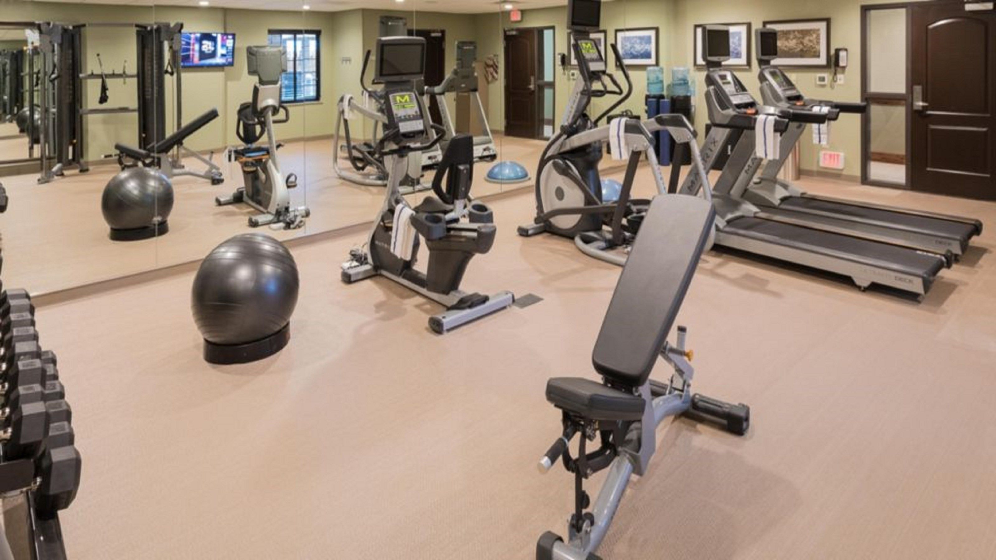 Un gimnasio con cintas de correr, elípticas y pesas libres.
