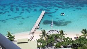 A beach with clear turquoise water, a pier, and palm trees. - Cozy Winter Getaway (Pocono Pines)