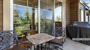 Un patio techado con una mesa, sillas, una parrilla y vistas del entorno.