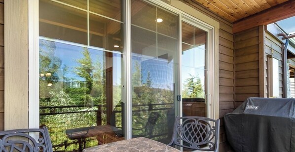 A covered patio with a table and chairs, a grill, and a sliding glass door leading to a deck. - Suncadia Townhome - Ridge Views ! 🏔️🏔️☀️ (Cle Elum)