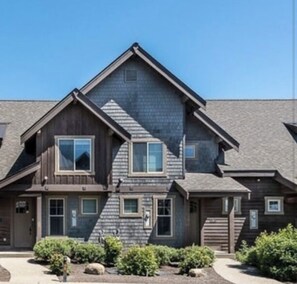A two-story wooden house with a gabled roof, multiple windows, and a front porch. - Suncadia Townhome - Ridge Views ! 🏔️🏔️☀️ (Cle Elum)