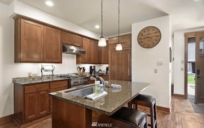 Enjoy cooking in this well-equipped kitchen with a large island, sink, and stainless steel range hood.