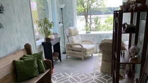 A living room with a geometric patterned rug, a wooden bench with green cushions, a wicker chair, a wooden side table, and a view of greenery outside. - WELCOME!  Are you looking to get away, to disconnect and relax? Look no further. (Montello)