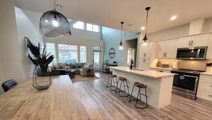 Eine moderne Küche mit Holztisch, Barhocker und einer zentralen Kochinsel.