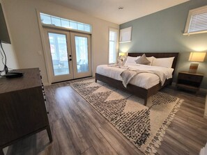 Ein Schlafzimmer mit Bett, Teppich, Schreibtisch und Fenster.