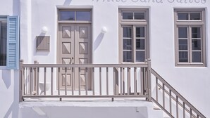 Un bâtiment à la façade blanche, avec une porte en bois et une fenêtre dotée d’un cadre blanc.