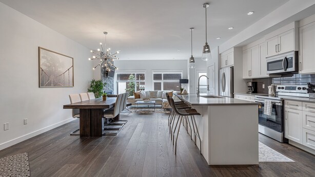 Une cuisine spacieuse équipée d’appareils modernes, un coin repas avec une grande table et un salon confortable avec un canapé et une table basse.