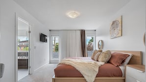 Une chambre à coucher avec un lit, une table de chevet, une chaise et une vue sur l’extérieur.