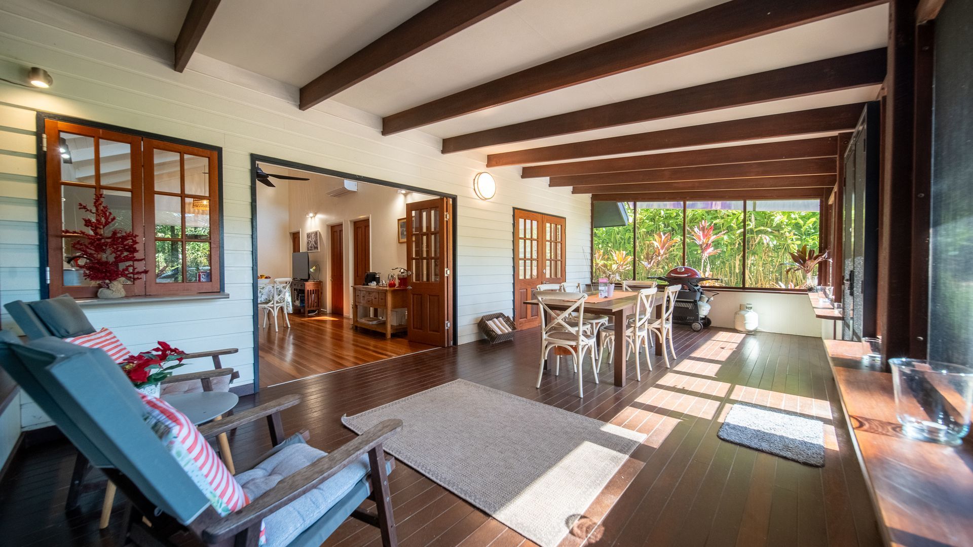 A spacious living area with a dining table, lounge chairs, and a view of the outdoors.