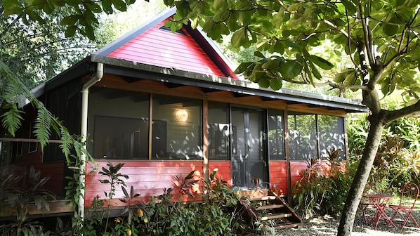 Een gebouw met rode dakpannen, grote ramen en een overdekte veranda.