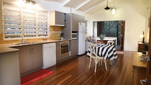 A modern kitchen with built-in appliances, a dining area with a striped tablecloth, and a view of the outdoors.