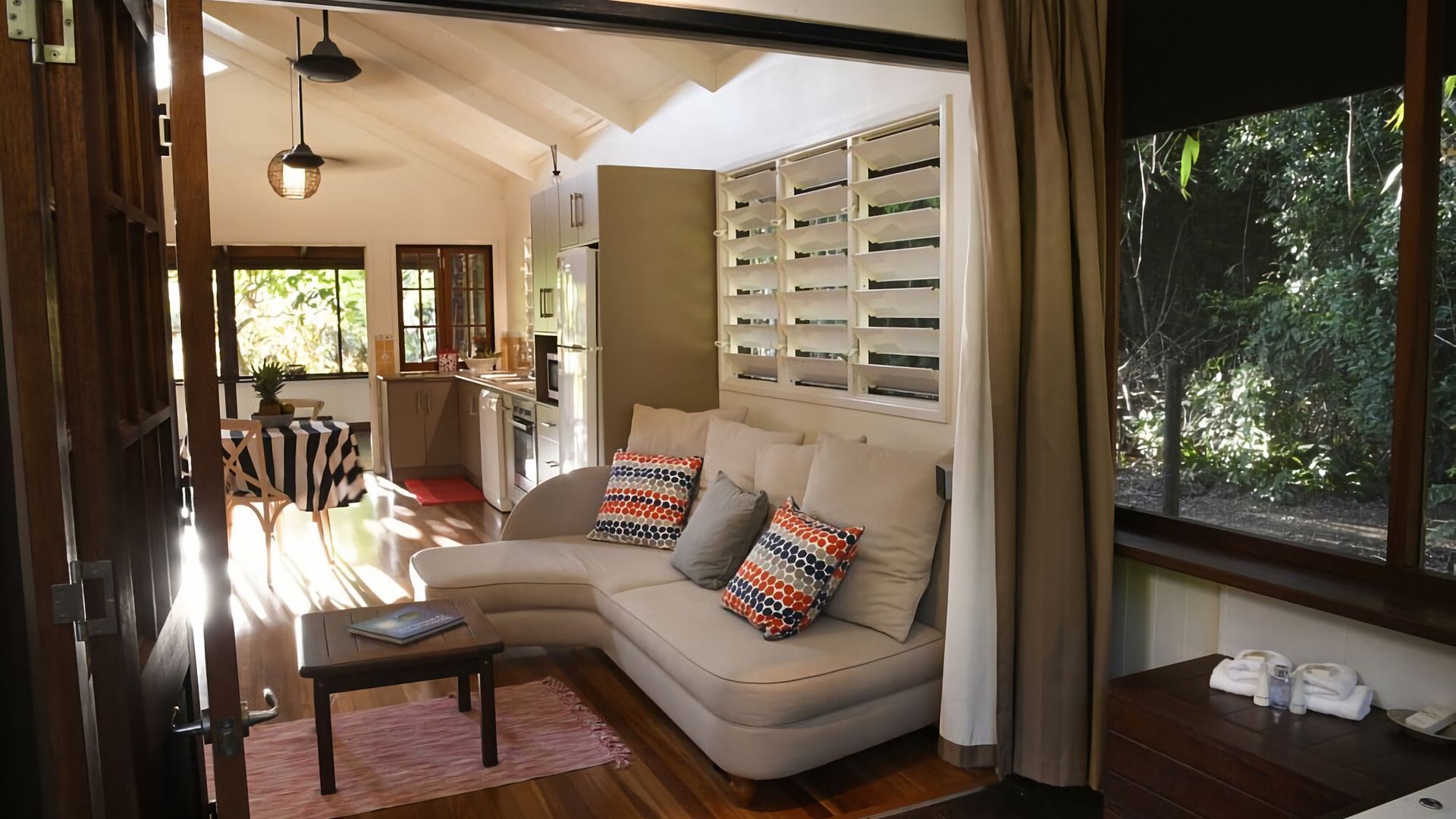 A modern living room with a sofa, a small table, and a kitchen area with cabinets.