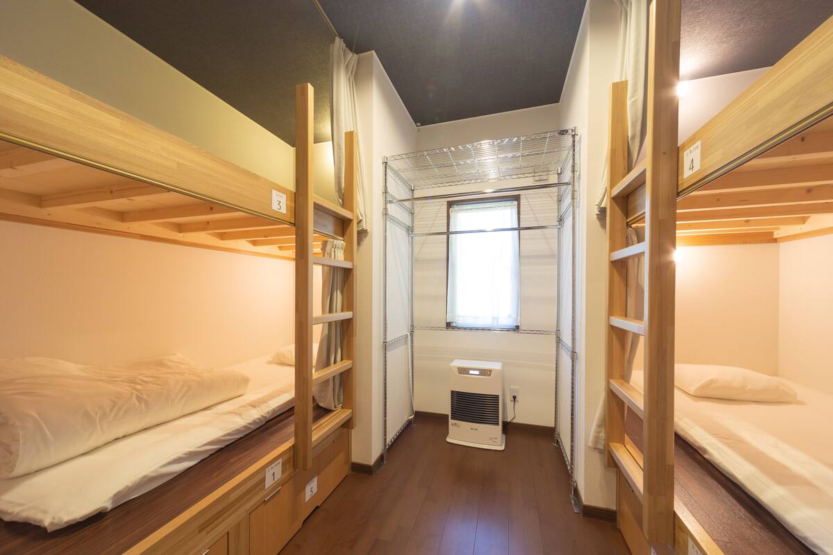 Een kleine kamer met stapelbedden, een raam en een verwarming.