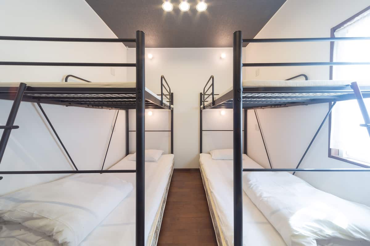 Een slaapzaal met stapelbedden, een houten vloer en een raam.