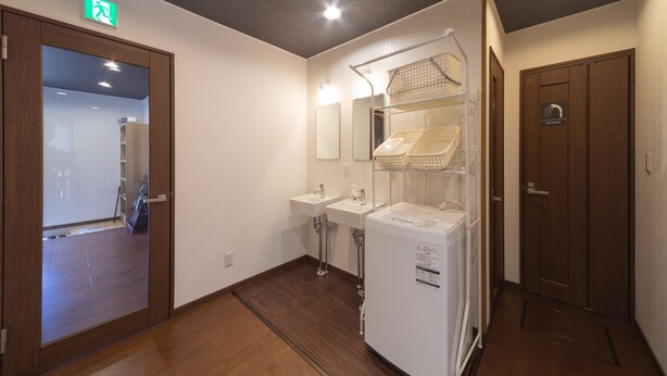 Un baño de hotel con dos lavamanos, un espejo, zona de ducha y una puerta con un letrero.