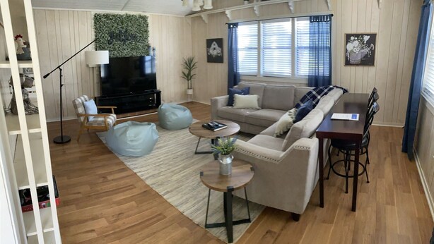 Una sala de estar moderna con sofá, mesa de centro, sillones de peluche y televisor.
