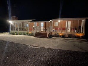 Een gebouw met twee verdiepingen, een overdekt terras, een trap en een omheind terras.