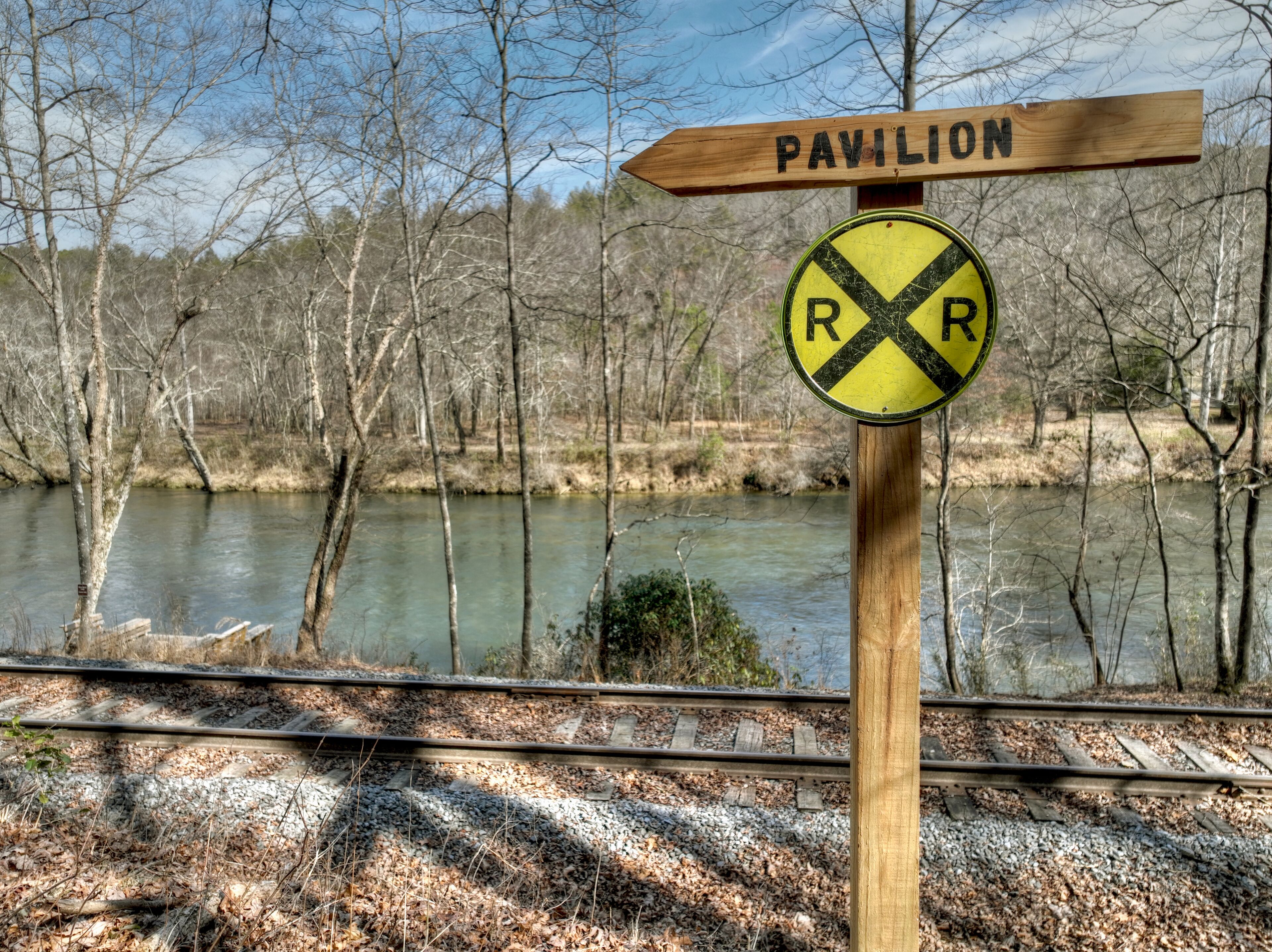 Un senyal de fusta amb un rètol que diu 'Pavilon' i un senyal de pas ferroviari.