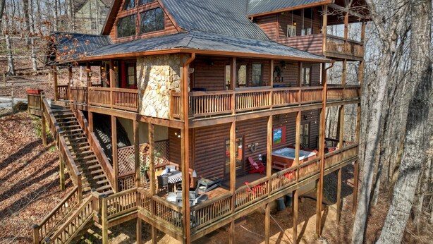A two-story log cabin with a balcony, a hot tub, and a deck area. - Riverfront Cabin w/ Private Dock, Putting Green, Game Room!  3.5mi 2 Blue Ridge (Blue Ridge)