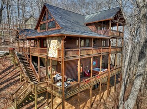A two-story log cabin with a balcony, a hot tub, and a deck area. - Riverfront Cabin w/ Private Dock, Putting Green, Game Room! 3.5mi 2 Blue Ridge (Blue Ridge)
