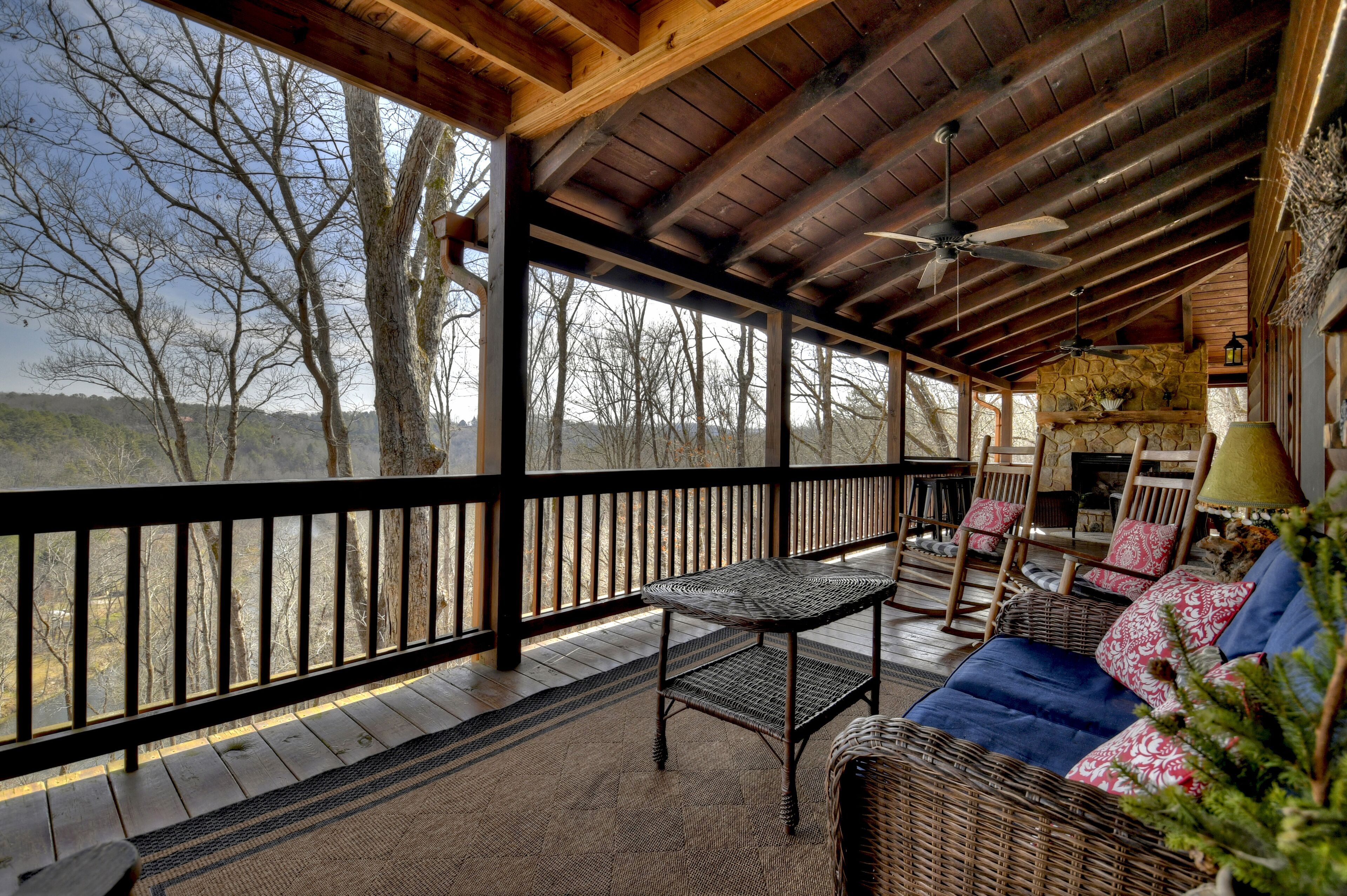 A covered outdoor area with a wooden ceiling, a table, chairs, and a sofa.