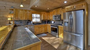 A spacious kitchen with wooden cabinets, a large island, stainless steel appliances, and a stone backsplash. - Riverfront Cabin w/ Private Dock, Putting Green, Game Room!  3.5mi 2 Blue Ridge (Blue Ridge)
