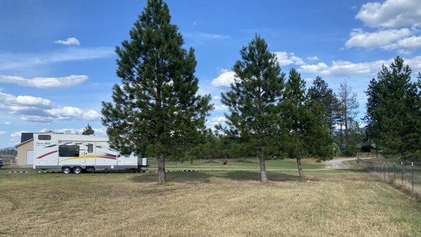 Um parque de campismo com uma caravana grande e várias árvores.