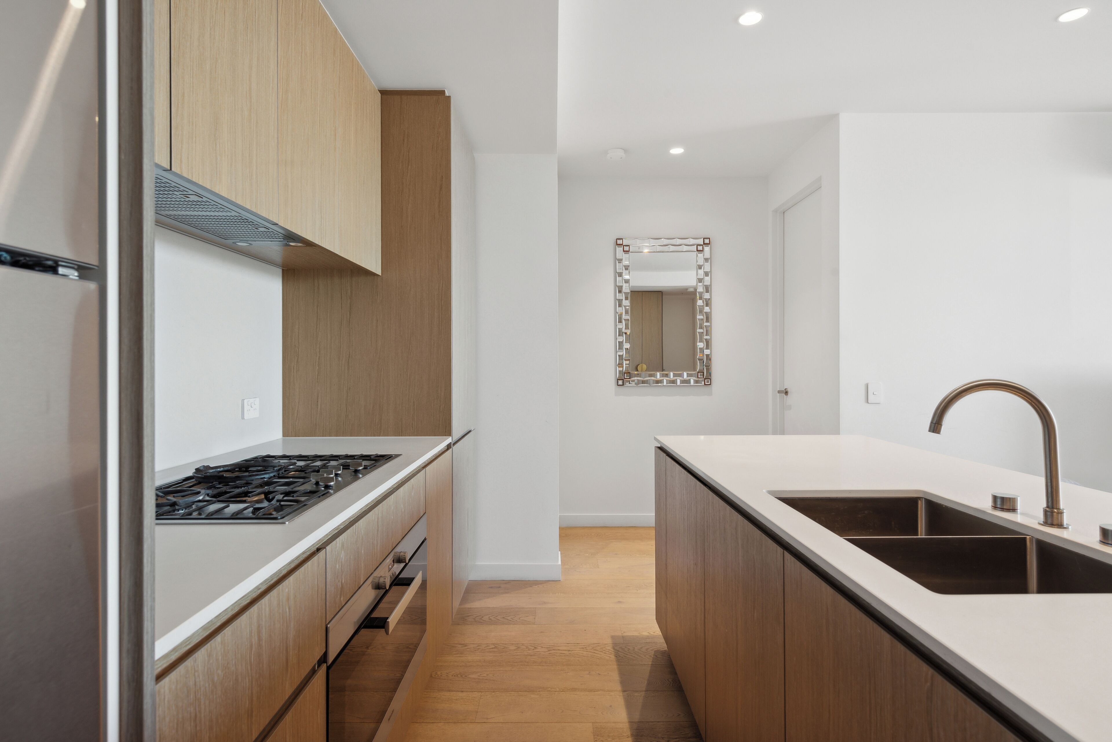Une cuisine moderne dotée d’un îlot central, d’appareils électroménagers en acier inoxydable et de meubles de rangement en bois.