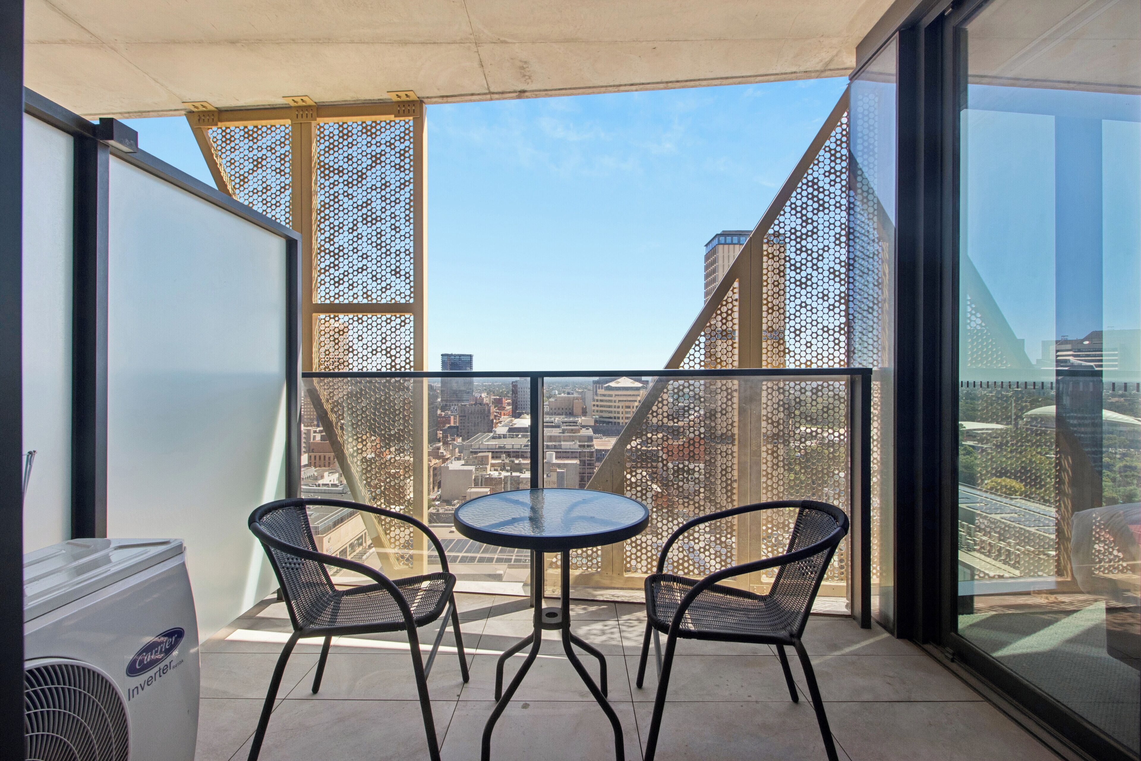 A balcony with a table and chairs, overlooking a cityscape.