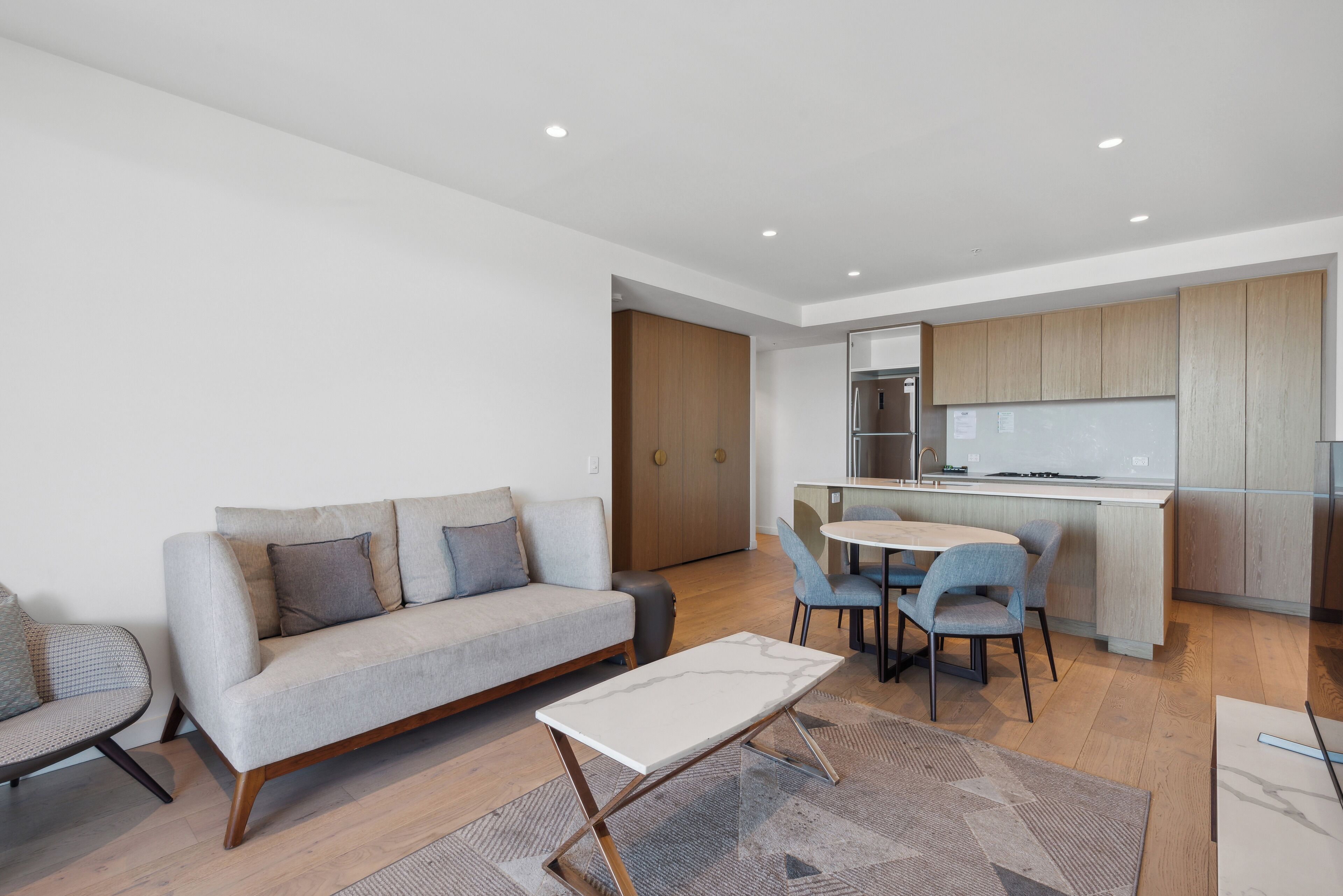 A modern living room with a sofa, a coffee table, and a dining area with chairs.