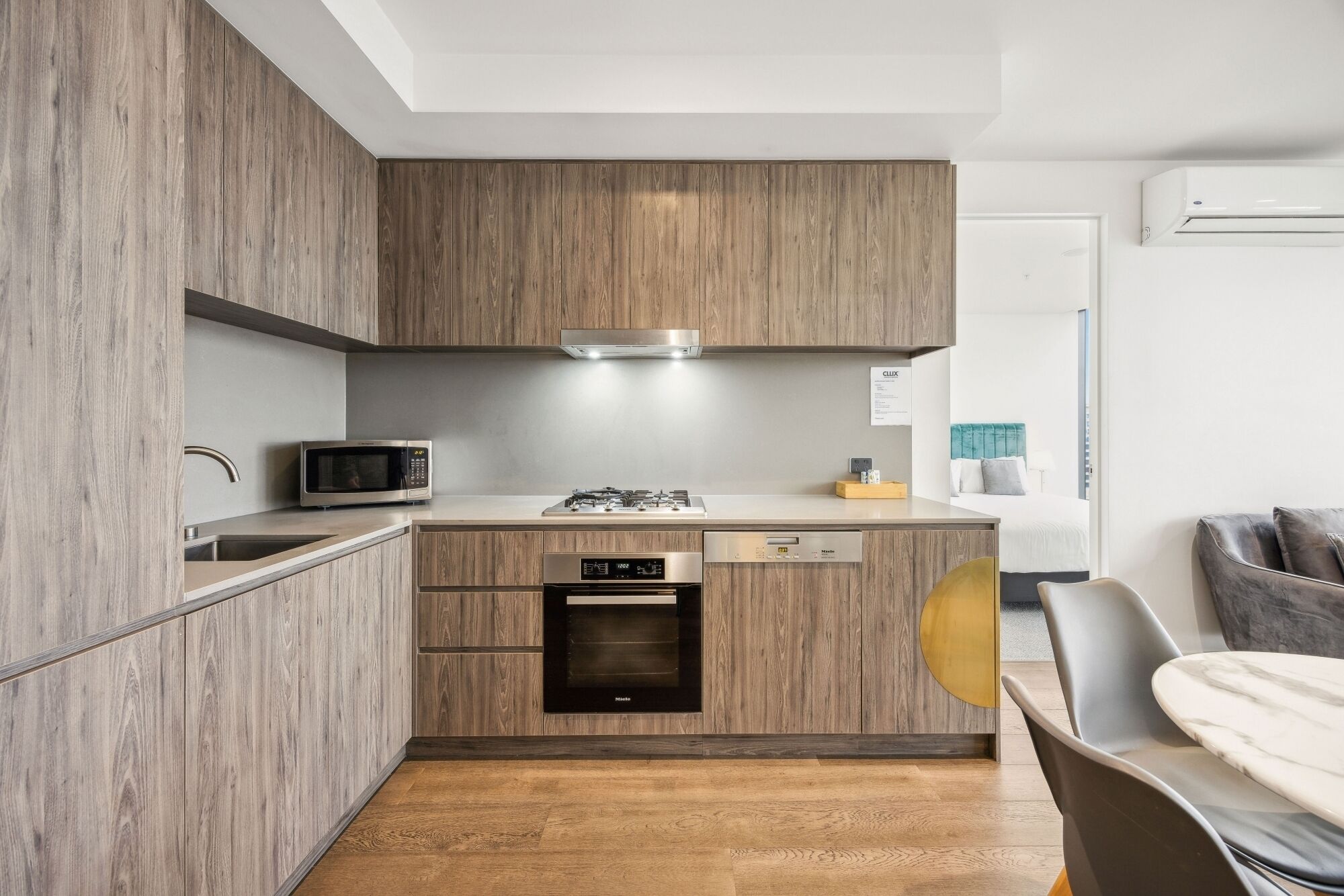 Une cuisine compacte dotée de meubles en bois, d’un four à micro-ondes, d’une cuisinière et d’un lave-vaisselle.