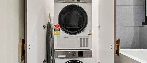 A stacked washer and dryer unit with a control panel, a caution label, and a water meter.
