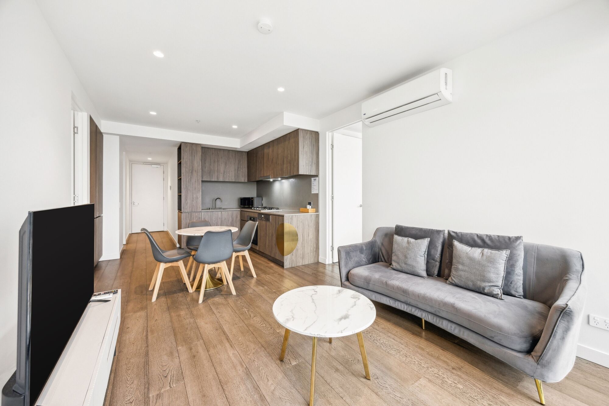 A modern living room with a grey sofa, a round coffee table, and a TV.