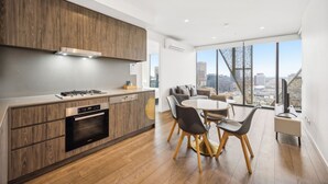Una cocina moderna con armarios de madera, horno empotrado y comedor con mesa y sillas redondas.