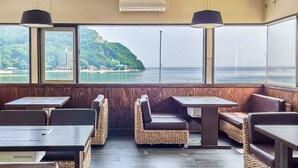 A restaurant with a view of a coastal landscape, featuring tables and booths with woven seating. - Seatiger Island In Shodoshima (Shodoshima)